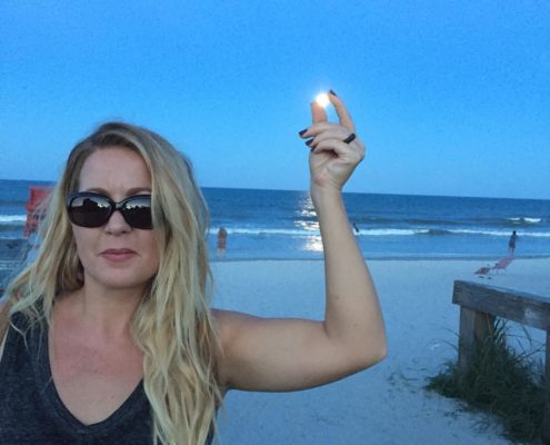 Abby Hinote capturing the full moon between her left hand on Jacksonville Beach, Florida